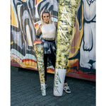 Eine Frau posiert vor einer bunten Wand mit übergroßen, bedruckten Objekten, die Cannabis-Joints darstellen, und repräsentiert damit die Marke "kleine knospe" für innovative CBD-Produkte.